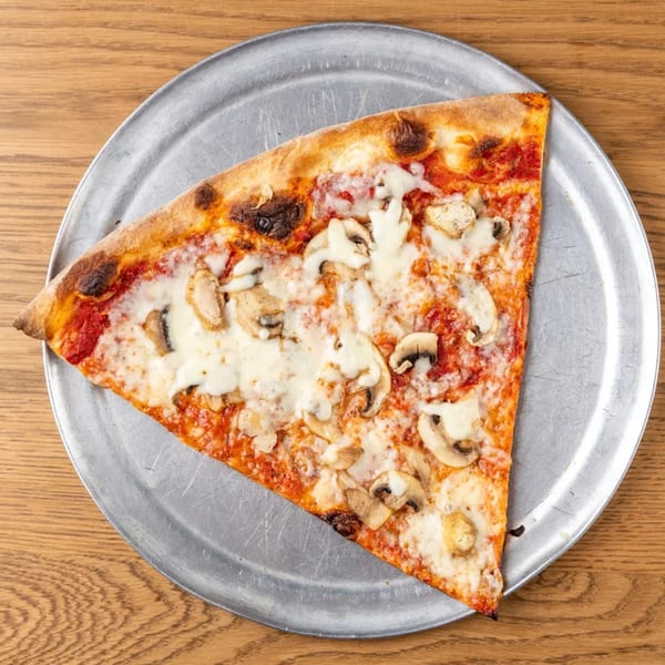 A single slice of mushroom pizza with melted cheese and tomato sauce on a metal tray.